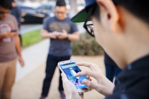 Fullerton, United States - July 13, 2016: Image of people playing pokemon go game on an iphone smartphone devices. Pokemon Go is a popular virtual reality game for mobile devices.