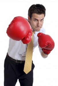 This is a close up photo of a businessman punching towards the camera. The focus is on the glove and falls off in the background.There are similar images in the lightbox below: