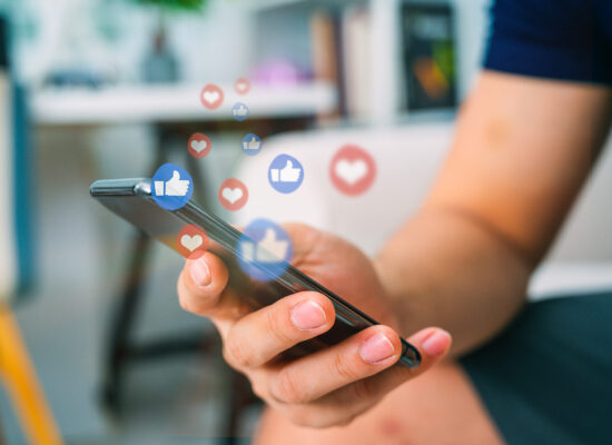 Hand holding smartphone with social media like and heart notifications, concept of online engagement and mobile marketing.